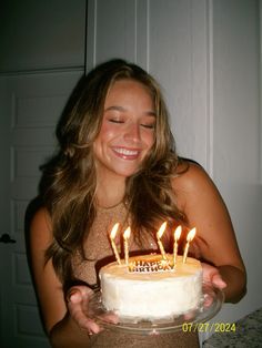 a woman holding a cake with candles on it in front of her face and smiling