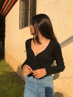 a woman standing in front of a building with her hands on her hips and looking off into the distance