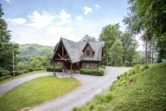 a large log cabin sits on the side of a road in front of some trees