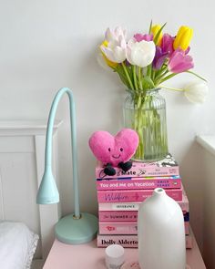 a pink table topped with books and a vase filled with flowers