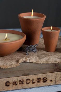 three candles sitting on top of a table next to a bowl with lavender in it