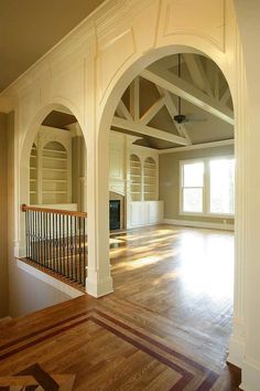 an empty living room with wooden floors and arches