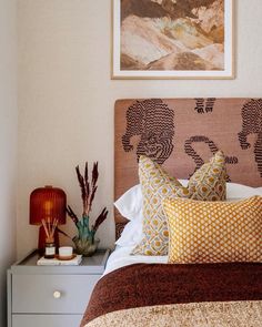 a bedroom with a bed, nightstand and painting on the wall above it's headboard