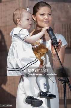 a woman holding a child while standing in front of a microphone