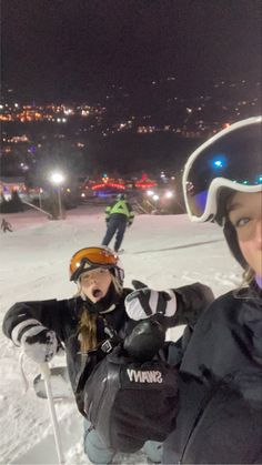 two young children sitting in the snow with skis and poles on their feet, one is wearing a helmet