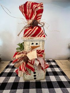 a snowman made out of candy canes sitting on top of a checkered table cloth