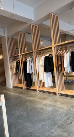 an open closet with clothes on hangers and pants hanging from the racks in front of it