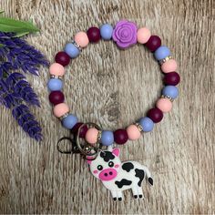 a cow charm bracelet with purple, pink and blue beads sits next to a lavender flower