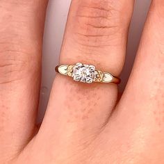 a woman's hand with a three stone diamond ring on it and the middle finger