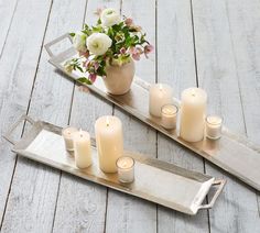 two trays with candles and flowers on them