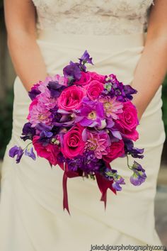 a bride holding a bouquet of purple flowers