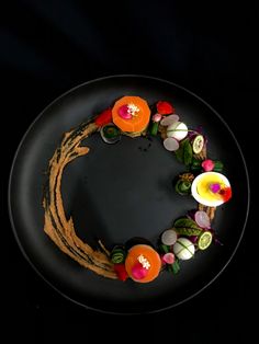 a black plate topped with an orange and pink flower wreath on top of it's side