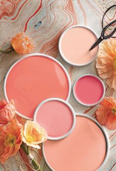 three different shades of pink and orange on a marble surface with flowers in the background