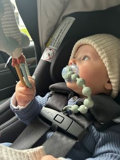 a baby in a car seat with a pacifier