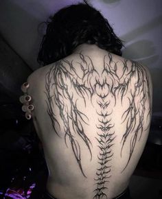 the back of a woman's body with an intricate tattoo design on her shoulder