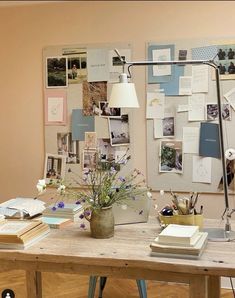 a wooden table topped with a lamp next to a vase filled with flowers and books