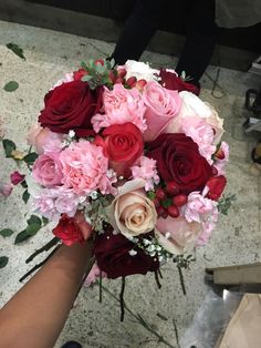 a bouquet of flowers is being held by someone's hand in the middle of a room