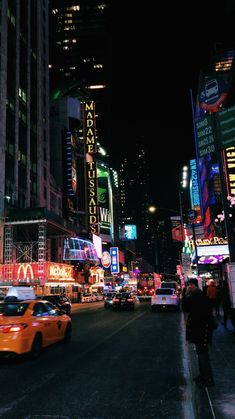 a busy city street at night with neon signs and cars on the road in front of tall buildings