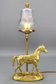 a golden horse lamp with a glass shade