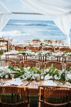 an outdoor dining area with tables and chairs set up for a wedding reception at the beach