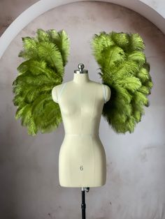 a white mannequin with green feathers on it