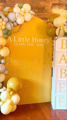 a baby shower with balloons and honeycombs on the wall next to a sign that says, a little honey is on the way