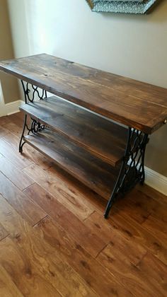 a wooden table sitting on top of a hard wood floor next to a painting hanging on the wall