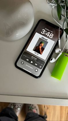 a cell phone sitting on top of a table next to a plant and headphones