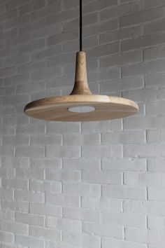 a white brick wall with a wooden light fixture hanging from it's center point