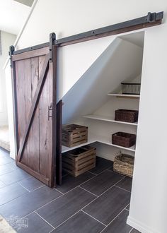 an open barn door in the corner of a room with shelves and baskets on it