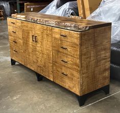 a large wooden cabinet sitting on top of a floor next to a black leather couch