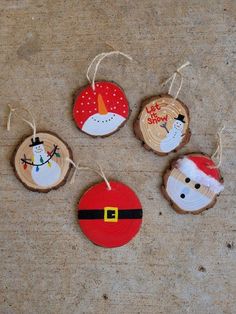 four wooden ornaments with santa claus and snowman faces hanging from twine strings on the floor