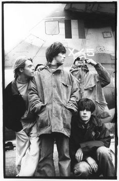 the rolling stones in front of an airplane with two men standing next to each other