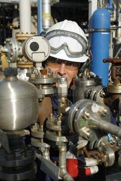 a man with goggles and safety glasses working on pipes in a factory stock photos