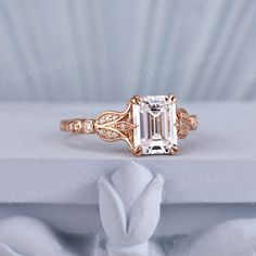 a fancy ring with an emerald center surrounded by white and rose gold filigrees