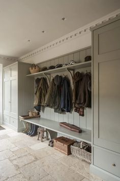 a coat rack filled with lots of coats and shoes next to a bench in a room