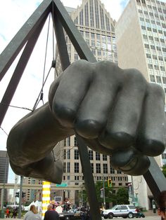 a large metal fist statue in the middle of a city