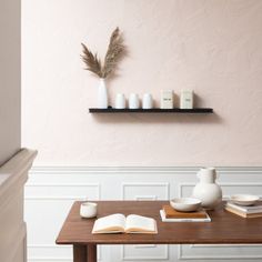 a wooden table topped with books and vases next to a shelf filled with candles