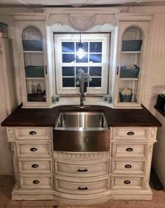 a kitchen sink sitting under a window next to a counter top with drawers and cupboards