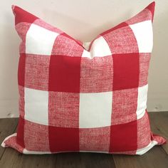 a red and white checkered pillow sitting on top of a wooden floor next to a wall