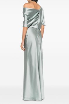 a woman in a long silver dress with one shoulder draped over her shoulders, looking back