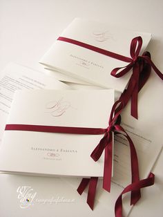 the wedding stationery is laid out on top of each other and tied with red ribbon