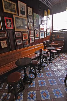 several tables and stools are lined up against the wall in a restaurant with many framed pictures on it