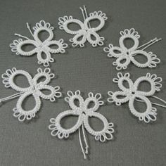 six white crocheted butterflies on a gray surface