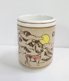 a coffee cup with a drawing of a horse on the front and mountains in the back