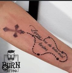 a person with a tattoo on their arm that has a cross and beads around it