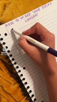 someone writing on a notebook with a pen