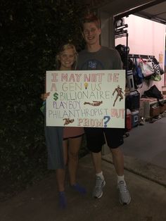 two people standing next to each other holding a sign