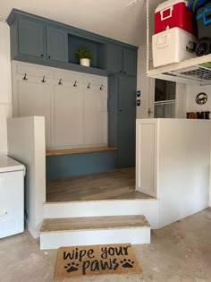 a garage with white cabinets and gray walls, an area rug that says wipe your paws