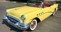 an old yellow car parked in a parking lot